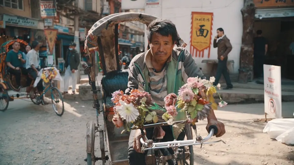 A rickshaw driver with flowers on his handlebars in a Himalayan town